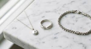 925 sterling silver necklace with round pendant, solitaire ring, and box chain bracelet displayed on white marble surface