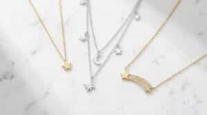 Types of star necklaces flat lay including dainty gold star pendant, layered silver star set, and shooting star necklace on white marble